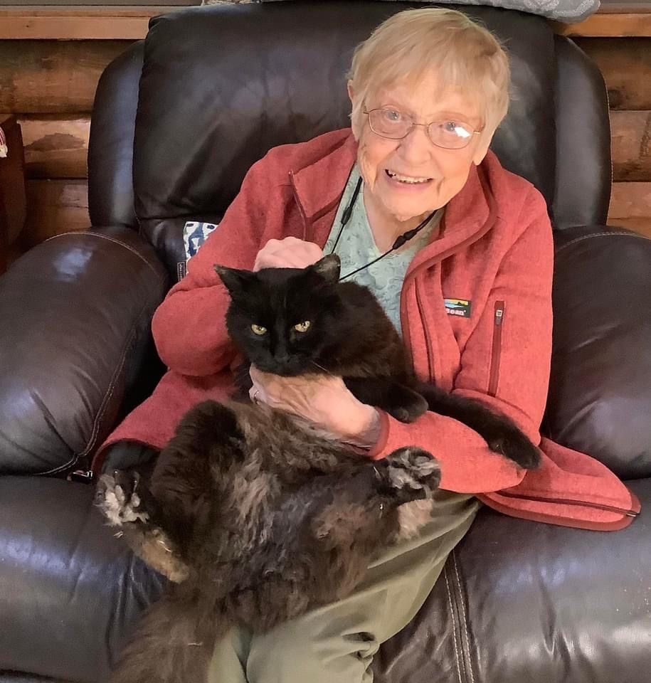Margaret Thompson smiling in her armchair holding her cat